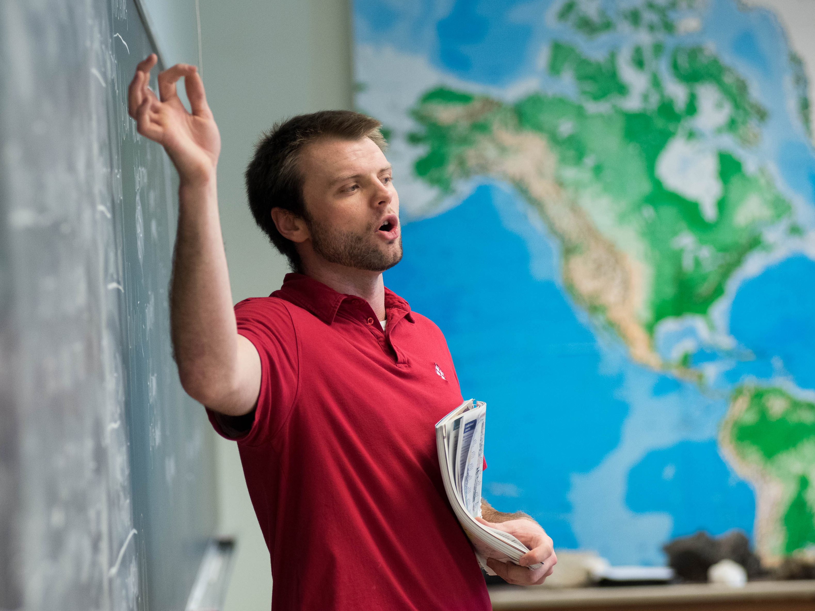 An instructor standing in front of a world map.