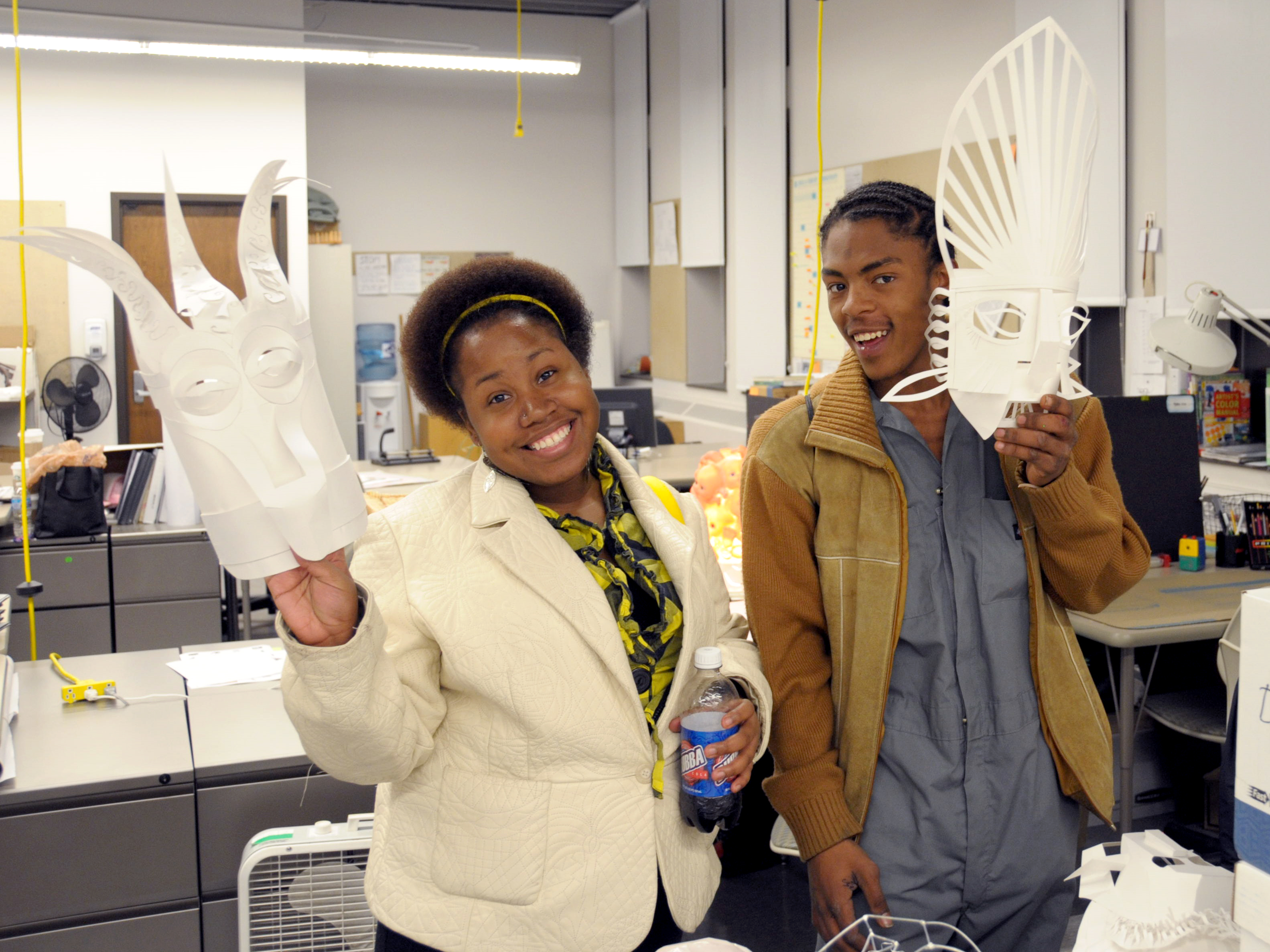 Two college students holding up paper craft pieces.